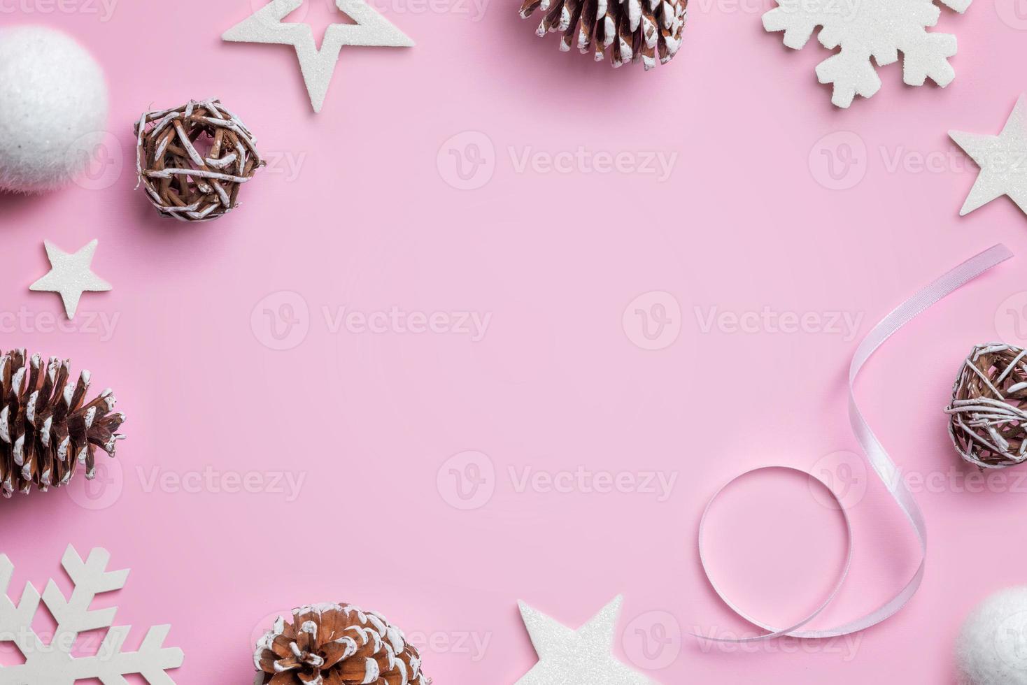 composizione di natale sulla scrivania rosa. stelle bianche, palline, fiocchi di neve e coni. sfondo di natale. vista dall'alto, posizione piatta foto