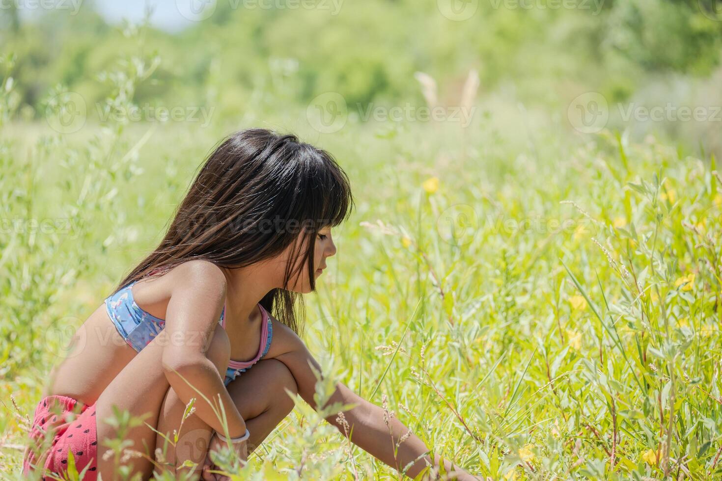 poco ragazza giocando con il fiori in crescita nel il prato. foto