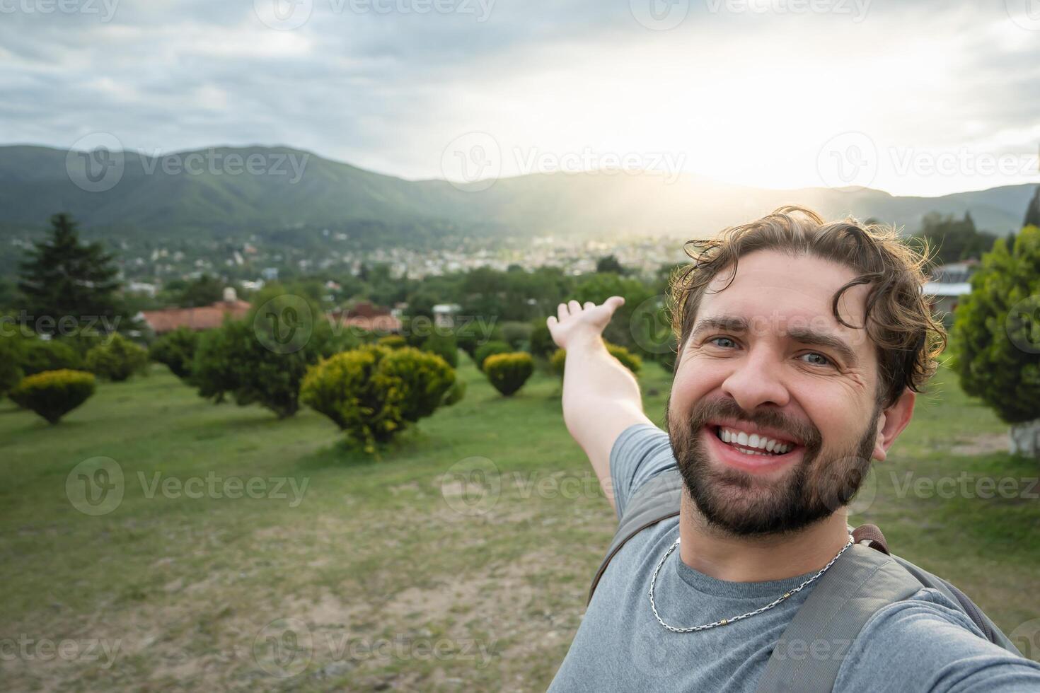 giovane escursionista assunzione un' autoscatto ritratto a il superiore di un' punto di vista. contento tipo sorridente a il telecamera. escursionismo, sport, viaggio e tecnologia concetto. luminosa filtro. foto