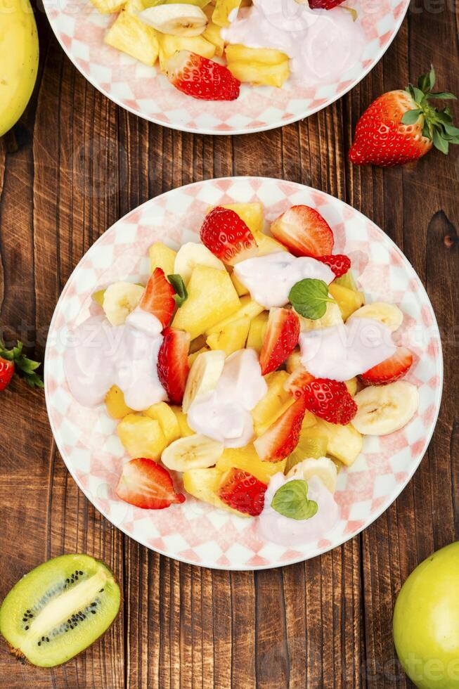 frutta insalata con Yogurt su di legno tavolo. foto