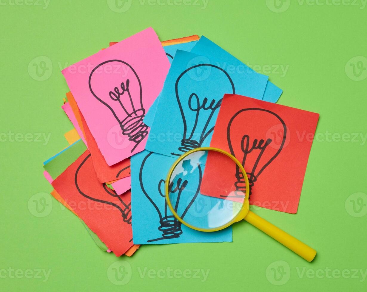 disegnato leggero bulbi su lenzuola di carta e un' plastica ingrandimento bicchiere, il concetto di ricerca per nuovo idee. foto