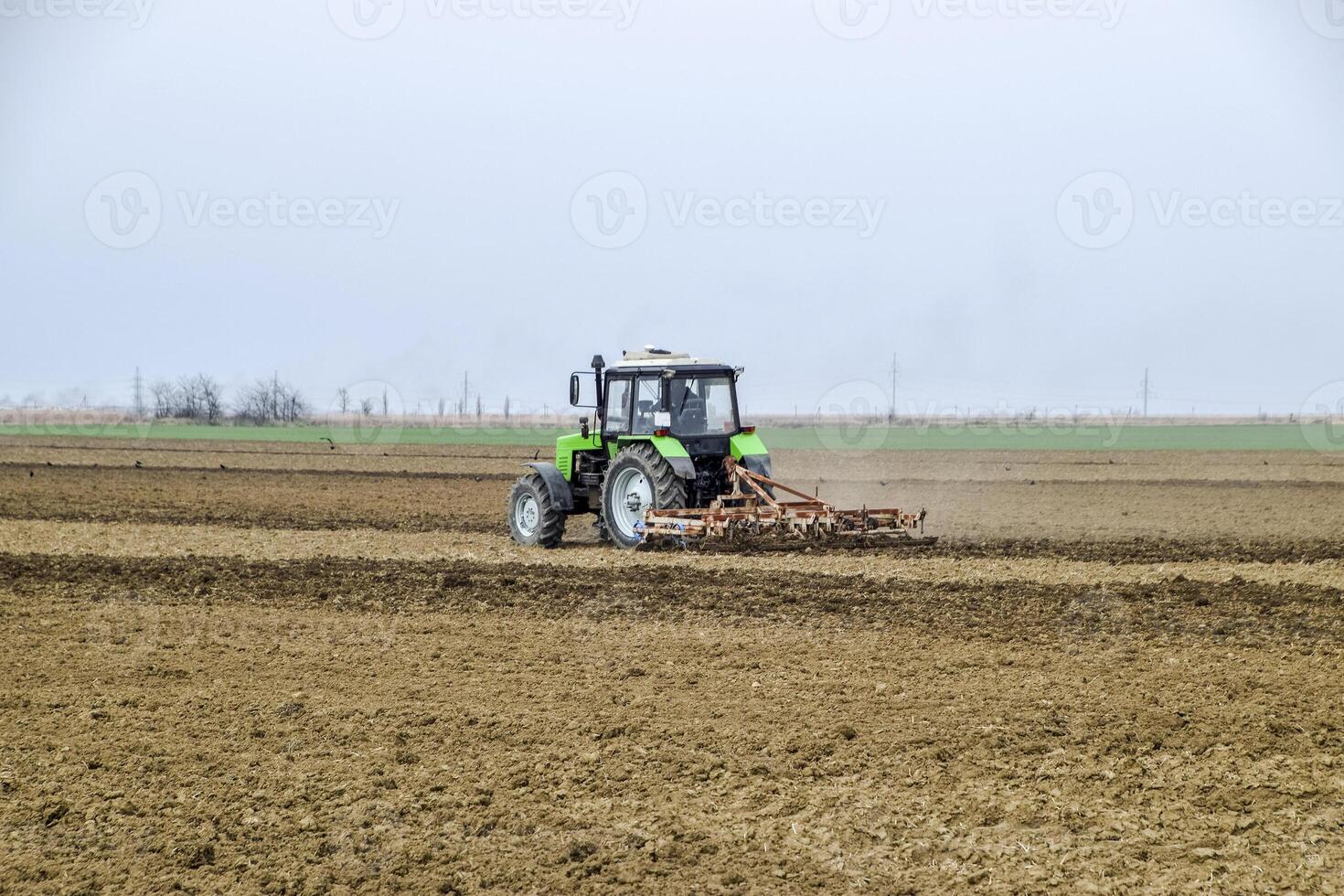 lussureggiante e allentare il suolo su il campo prima semina. il trattore aratri un' campo con un' aratro foto