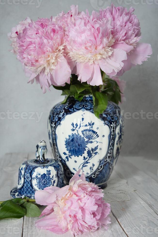 rosa lussuoso peonie nel un antico Cinese vaso con blu ornamento, primavera foto