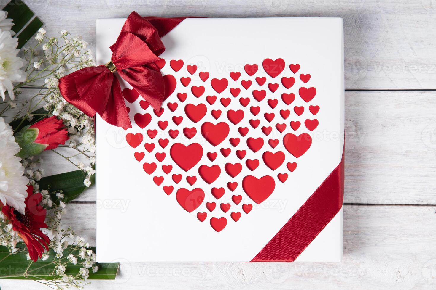 San Valentino giorno regalo, rosso cuore pralina scatola e fiore mazzo su bianca tavolo foto