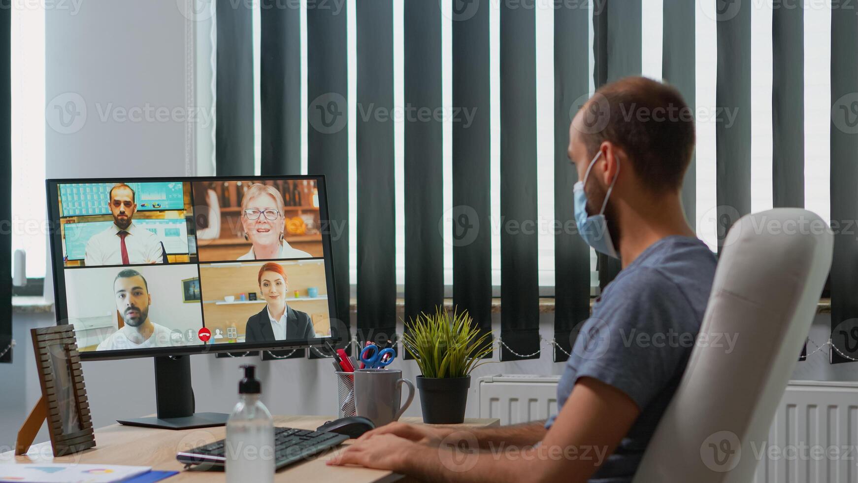 attività commerciale uomo con protettivo viso maschera parlando su video chiamata su pc mentre Lavorando nel nuovo normale ufficio durante coronavirus pandemia. libero professionista avendo in linea conferenza incontro utilizzando Internet tecnologia foto