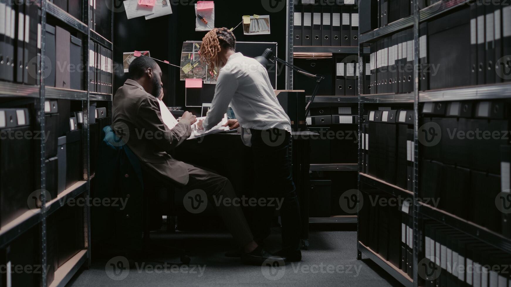 polizia agenti fare sfondo controlli per indagine nel archivio camera, l'esame Astuccio File e sorveglianza metraggio per scoprire indizi. investigatori Lavorando con fisico evidenza. foto