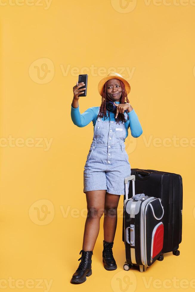 gioioso turista chat su video chiamata nel studio, sorridente donna utilizzando a distanza Teleconferenza incontro su vacanza viaggio. femmina modello godendo video conferenza chiamata e in viaggio all'estero. foto