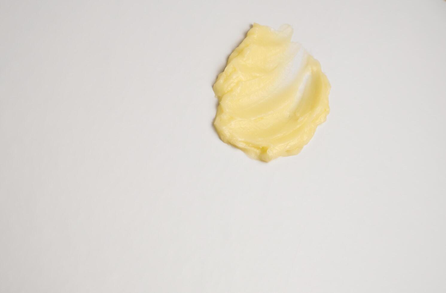 cosmetico prodotti cremoso giallo macchia struttura su un' bianca sfondo. il struttura di naturale cosmetici capelli maschera, crema, macchia foto