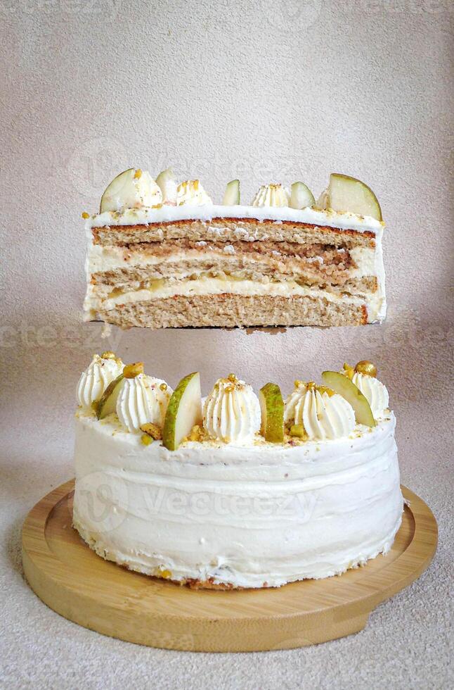 bianca torta tagliare nel Due metà con bianca crema e fette di Pera su un' bianca piatto foto