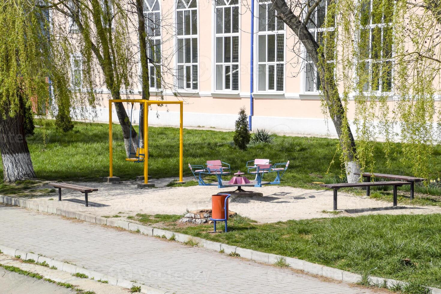 mini terreno di gioco sotto salice alberi. swing e giostra Il prossimo per il panchine. foto