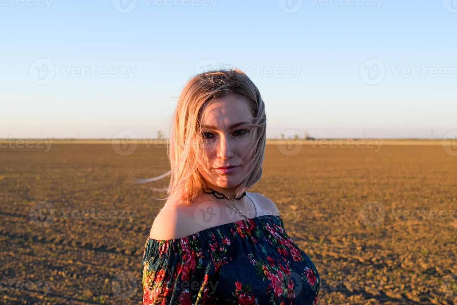 donna nel un' arato campo nel un' rosso nero vestito su un' tramonto sfondo. foto