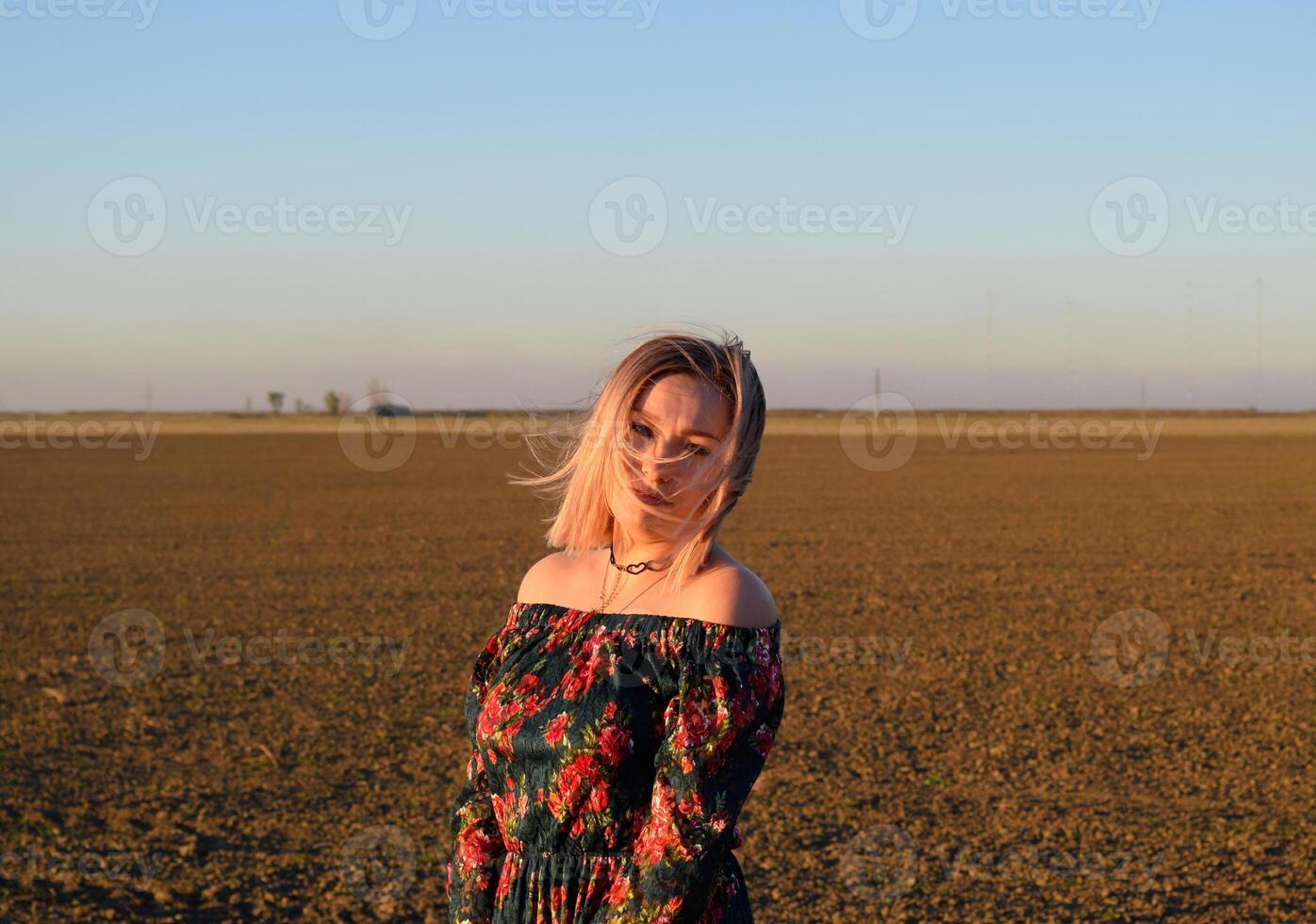 donna nel un' arato campo nel un' rosso nero vestito su un' tramonto sfondo. foto