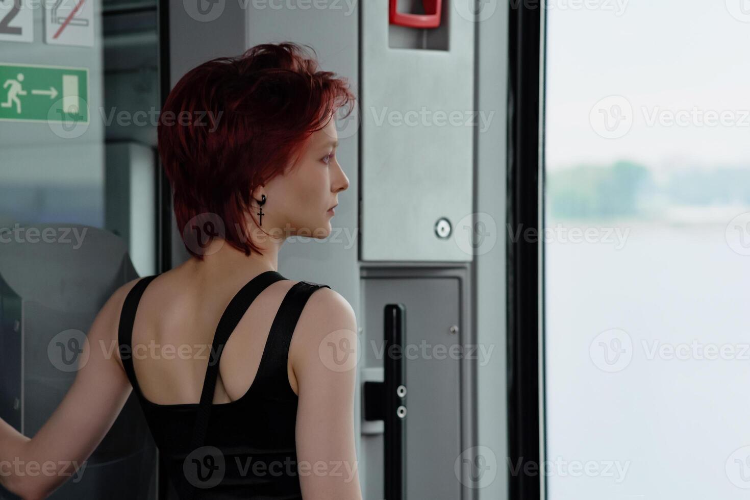 ragazza sta nel un' carrozza di un' in movimento suburbano treno nel davanti di il porta, guardare a il mare foto