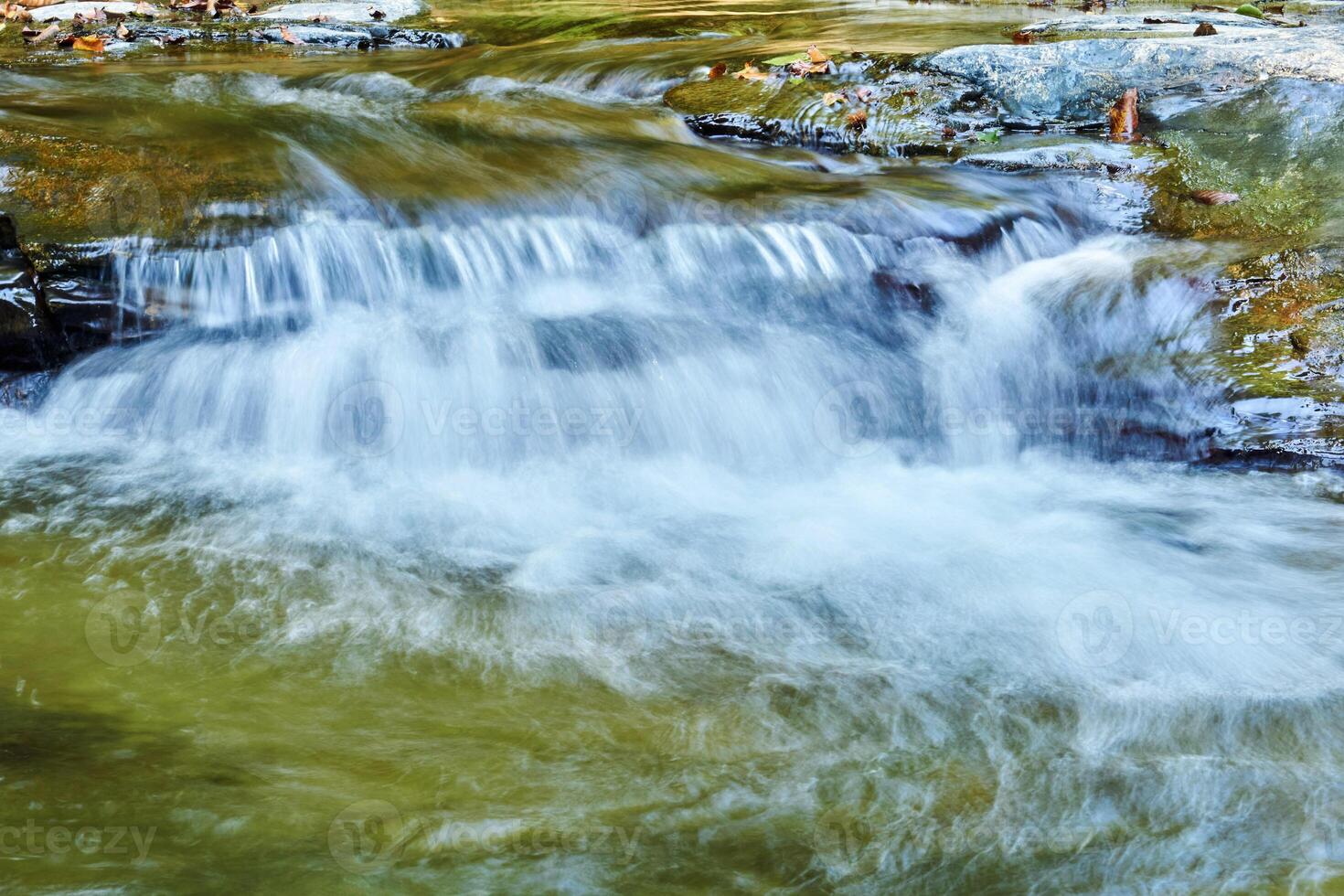 piccolo cascata nel un' montagna ruscello fra rocce, il acqua è sfocato nel movimento foto