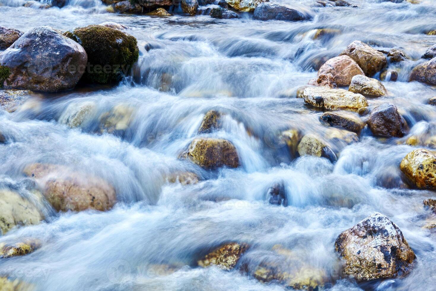 sfondo - un' montagna ruscello nel un' roccioso canale, il acqua è sfocato nel movimento foto