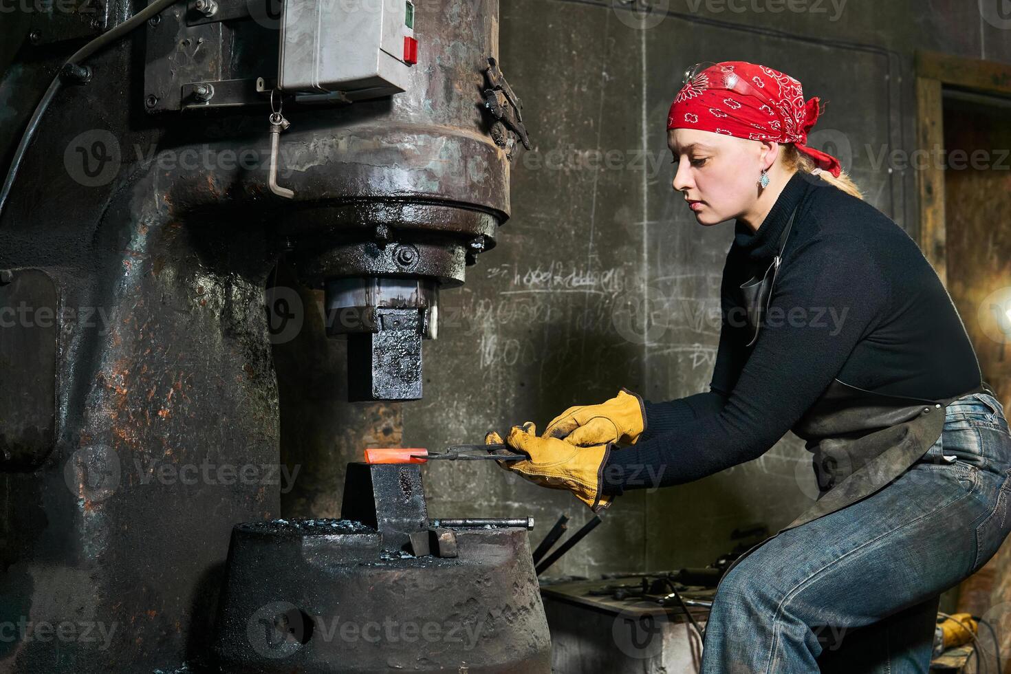 donna metallo artista processi un' caldo pezzo in lavorazione con un' energia martello foto