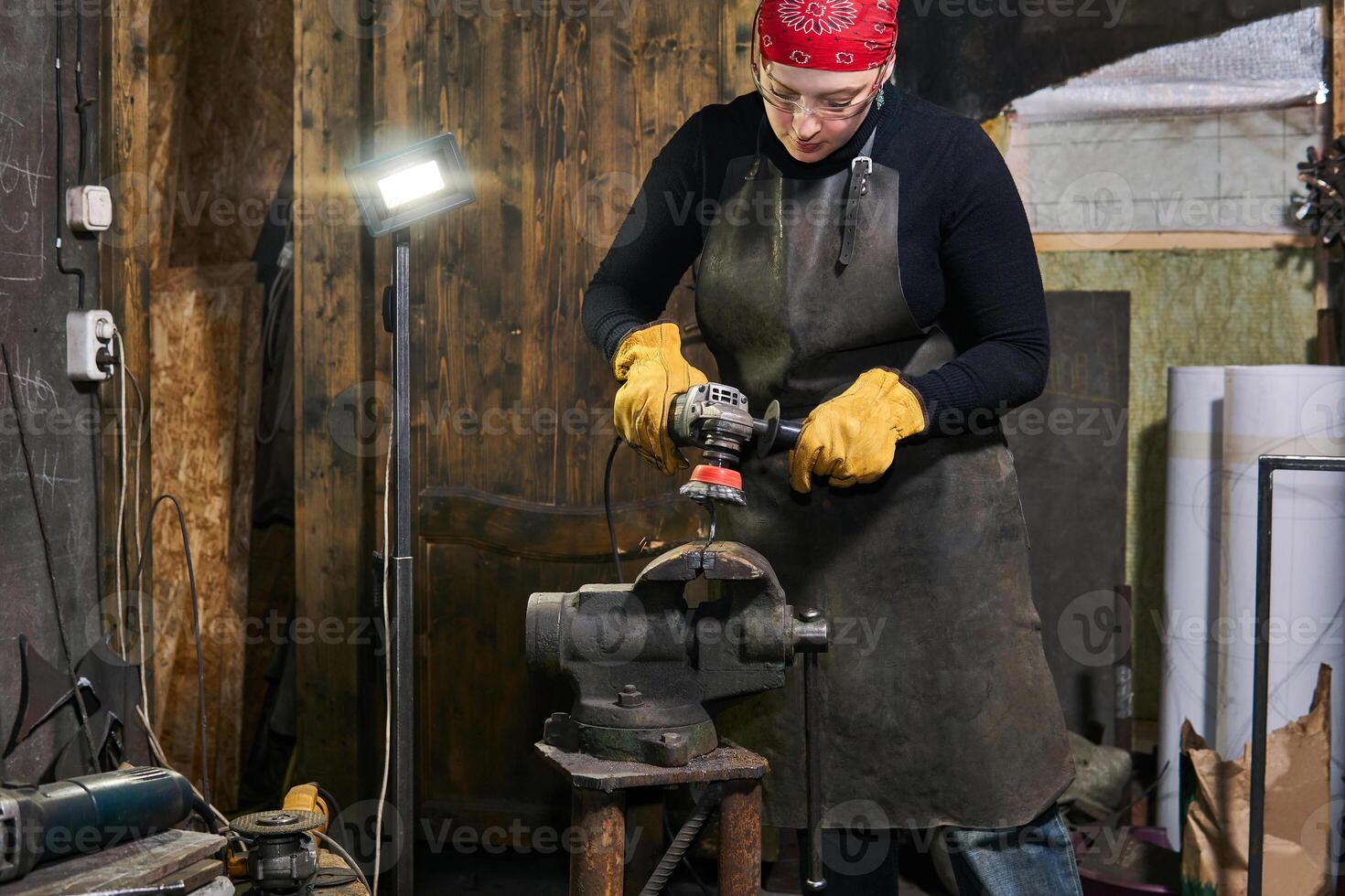 femmina artigiano processi un' metallo opera d'arte con un angolo macinino foto