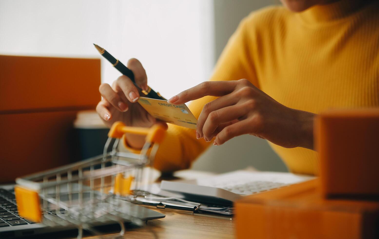 giovane donna Tenere un' smartphone, tavoletta mostrando pagamento successo e credito carta con giallo pacco scatola come in linea shopping concetto nel ufficio foto
