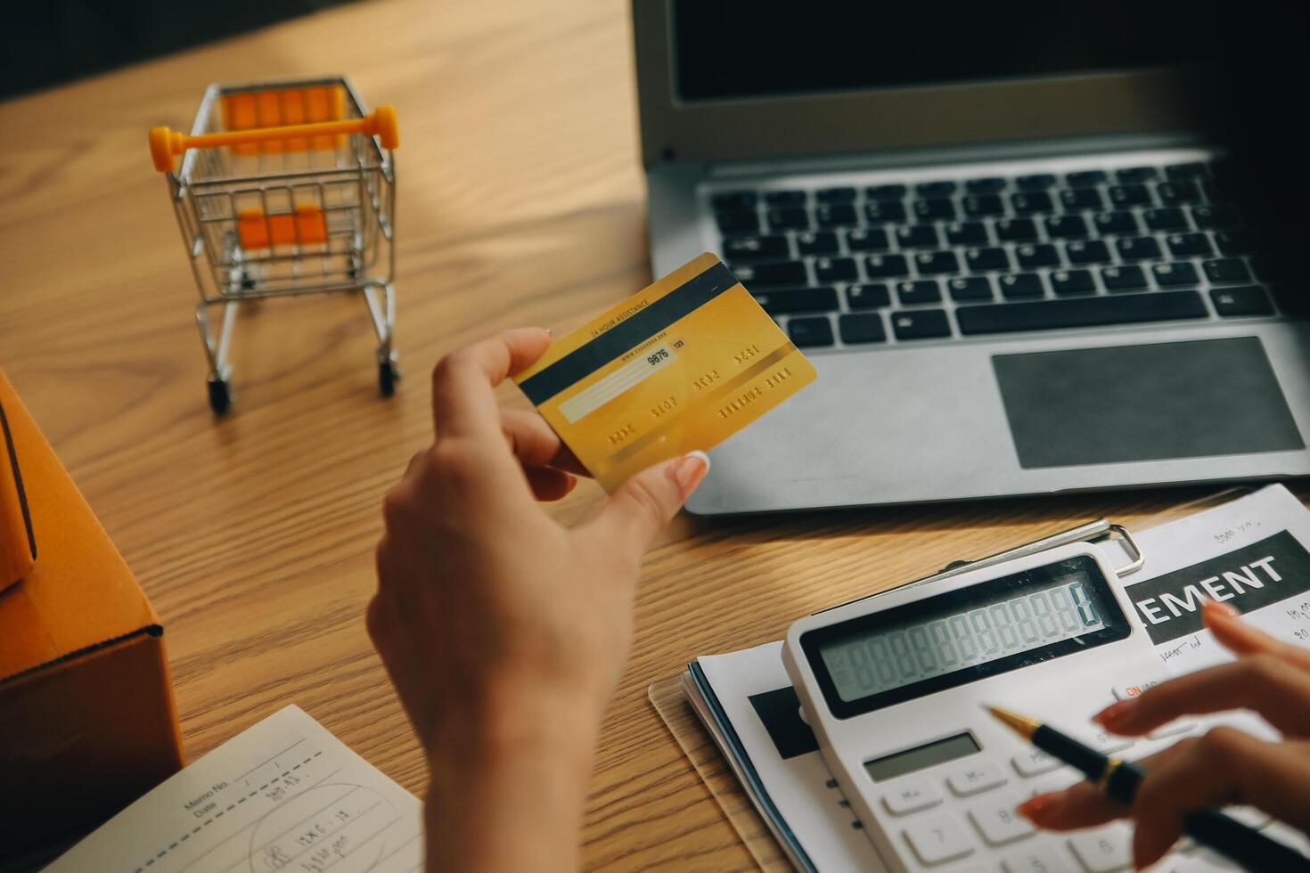 giovane donna Tenere un' smartphone, tavoletta mostrando pagamento successo e credito carta con giallo pacco scatola come in linea shopping concetto nel ufficio foto