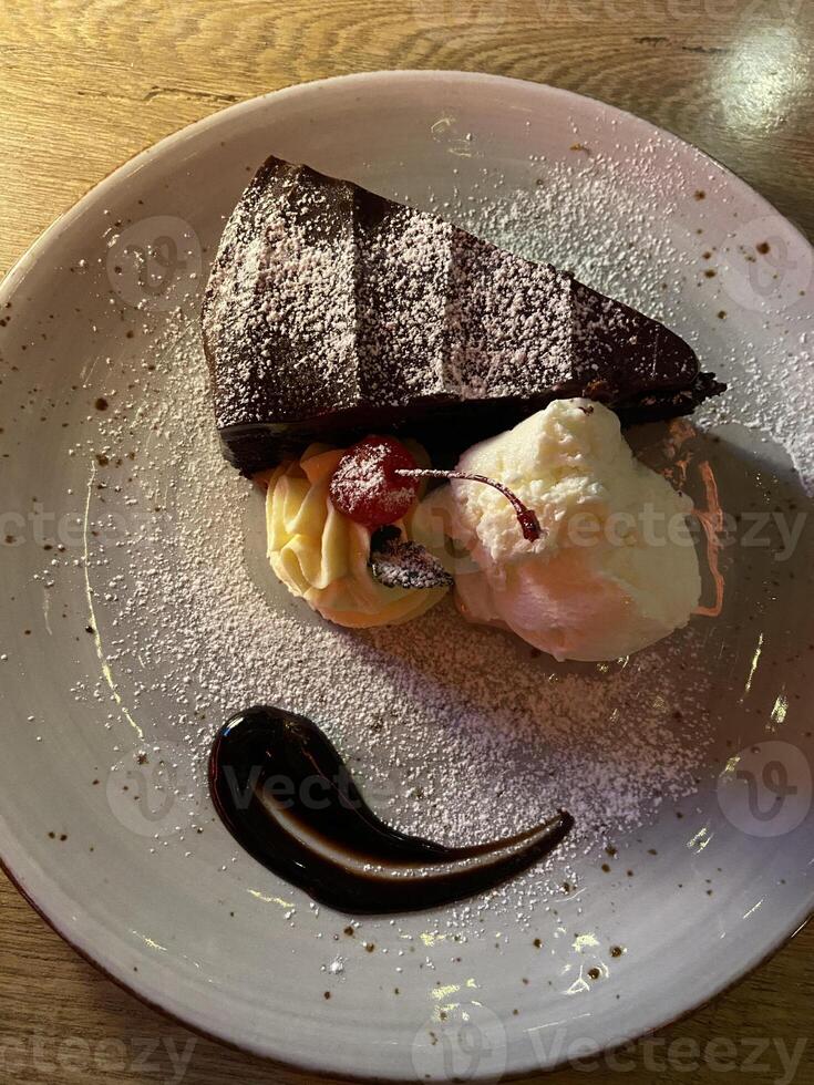 piatto di cioccolato torta con crema, un' ciliegia e glassatura zucchero su superiore foto