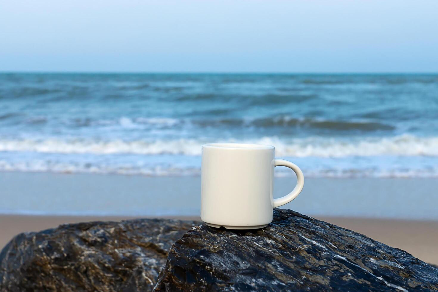 bianca caffè tazza su il roccia a mare. foto