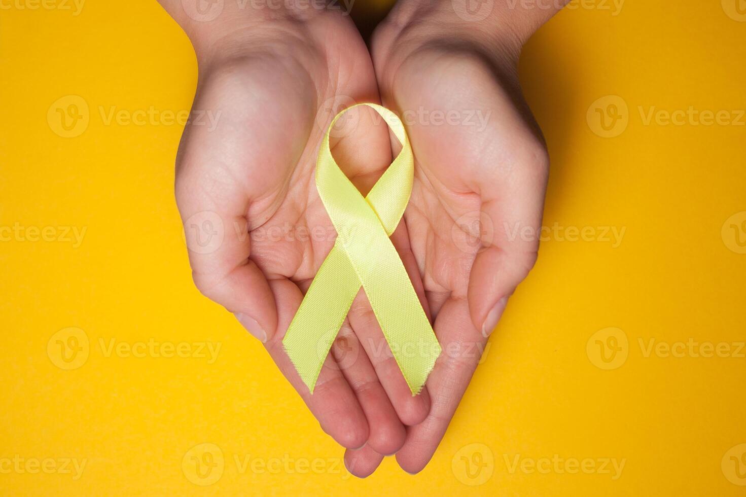 oro nastro per bambini come un' simbolo di infanzia cancro consapevolezza. giallo nastro su mano foto