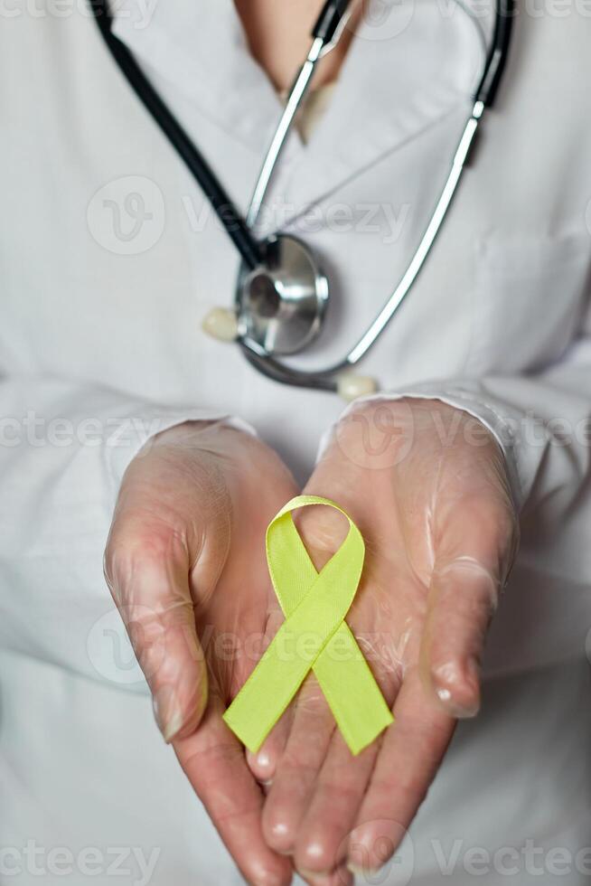 giallo cancro consapevolezza nastro nel il mani di un' medico. mondo cancro giorno foto
