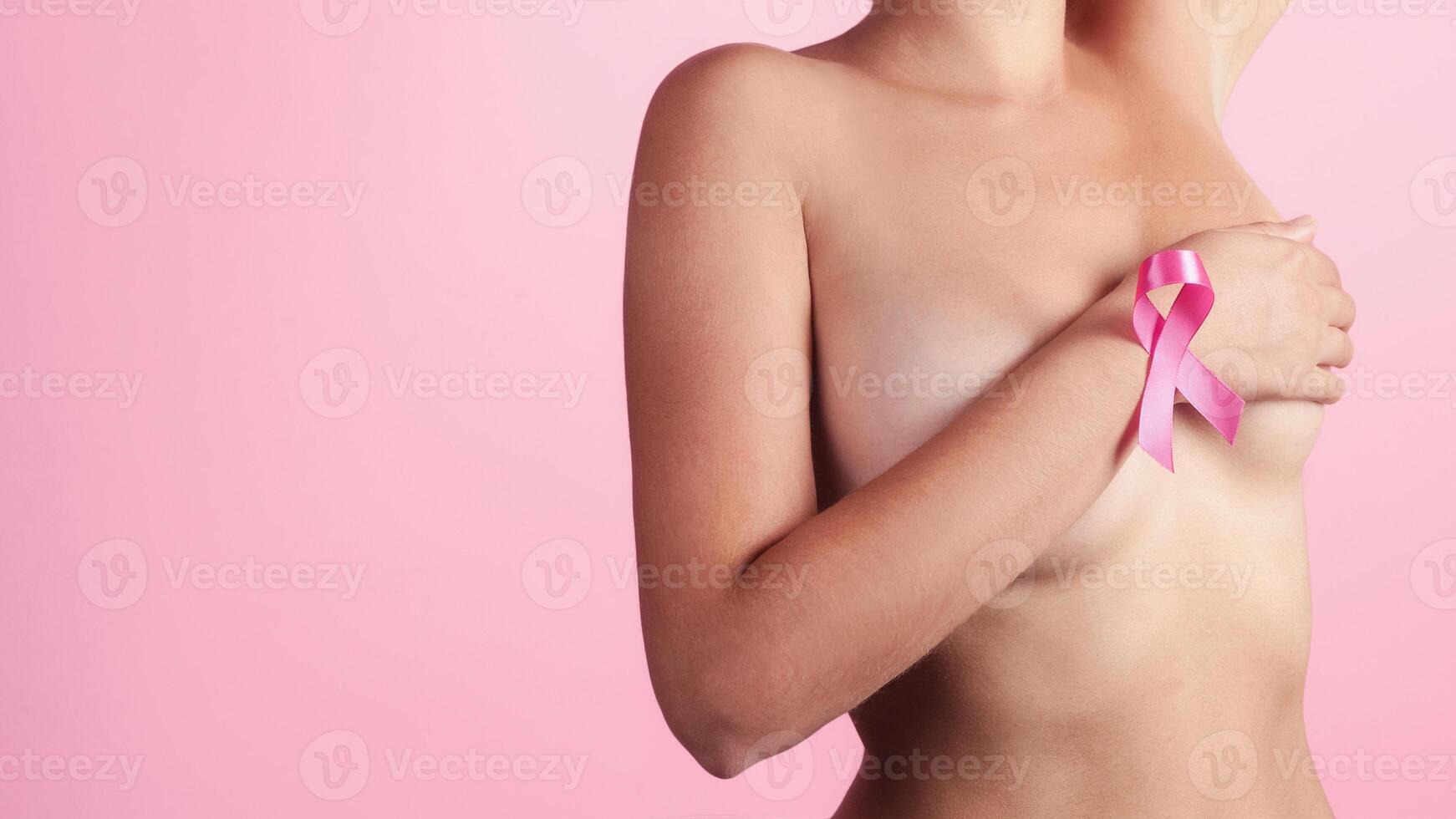 giovane donna l'esame sua Seno per granuli o segni di Seno cancro. rosa nastro. consapevolezza di maligno tumore foto