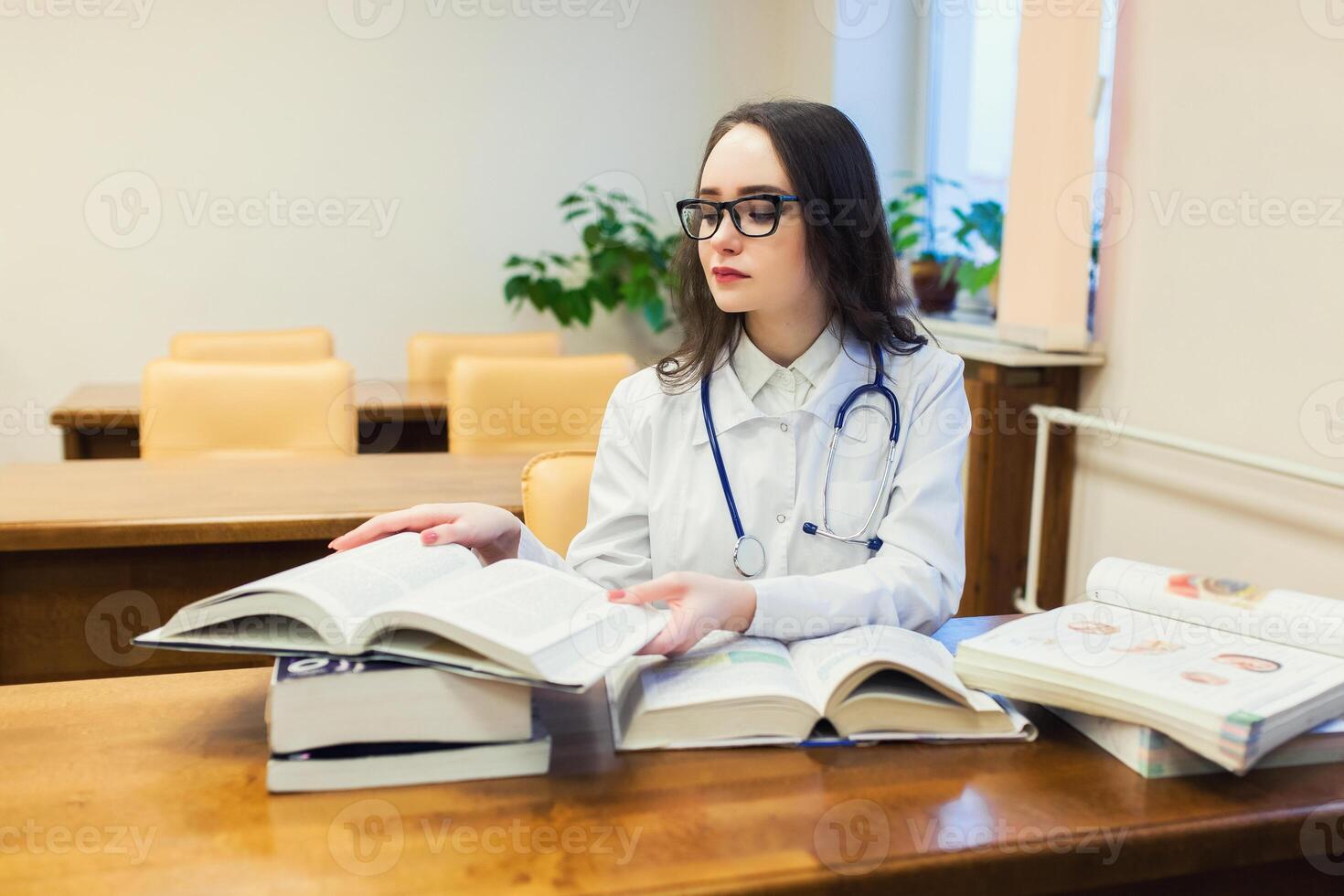 un' medico alunno per libri di testo. il studia di chirurgia di un' bellissimo ragazza nel il biblioteca foto