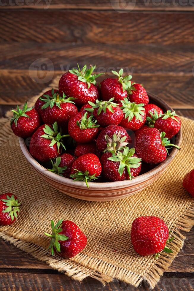 rosso maturo fragola su di legno sfondo. fresco fragole nel ciotola foto