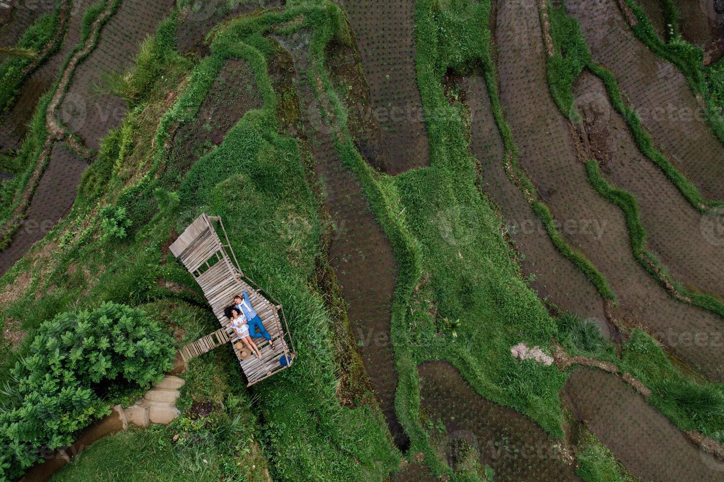 aereo Visualizza su superiore. Due Gli amanti di giovane persone menzogna su un' di legno ponte. contento coppia in viaggio a Bali, riso terrazze di tegalalang, ubud. luna di miele estate viaggio a Indonesia. contento le persone. foto