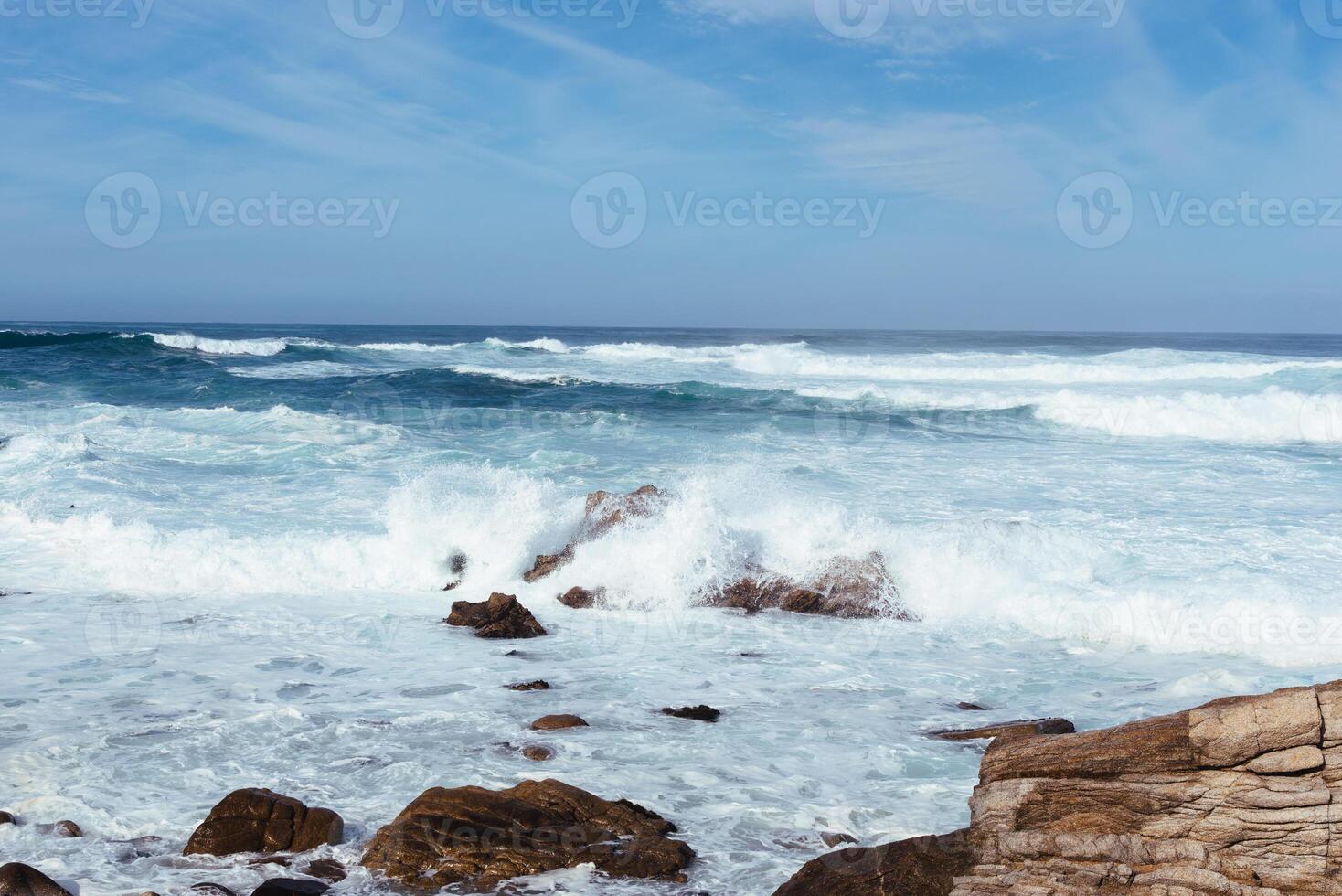 bianca onde colpire rocce su il oceano riva foto