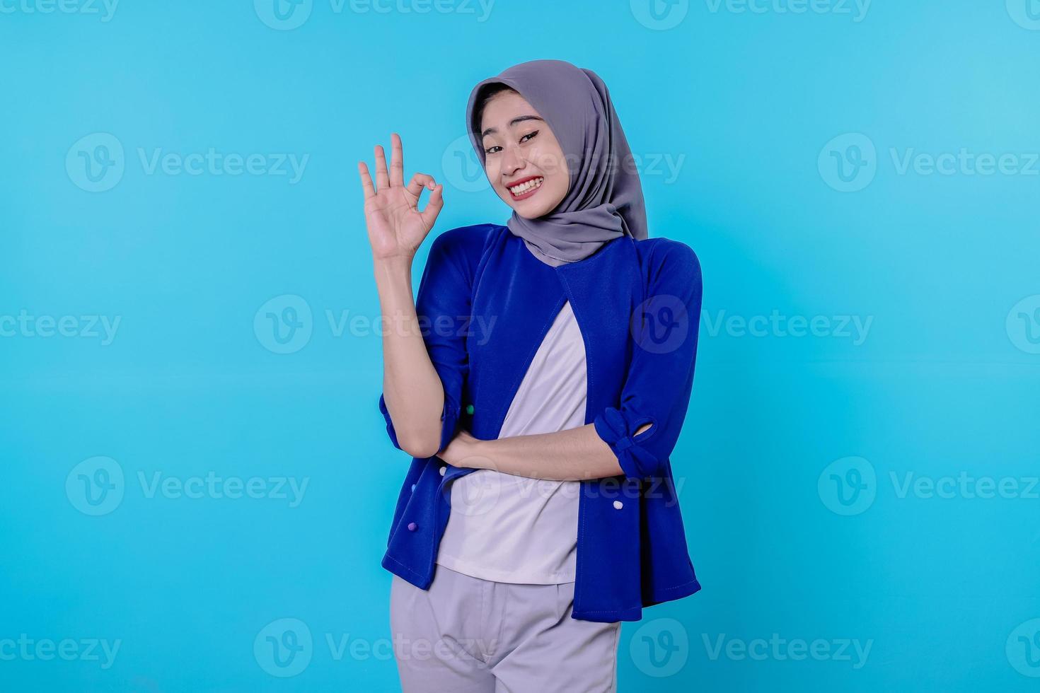 donna allegra con l'hijab che mostra il segno ok, sorridente, dire di sì, incoraggiare a comprare qualcosa, fare un buon gesto foto