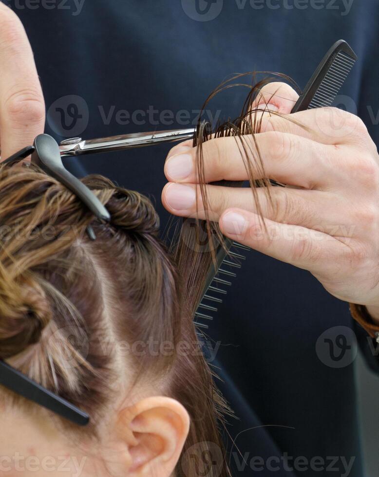 stilista taglio un' filo di capelli per un' cliente con professionale forbici. alto qualità foto