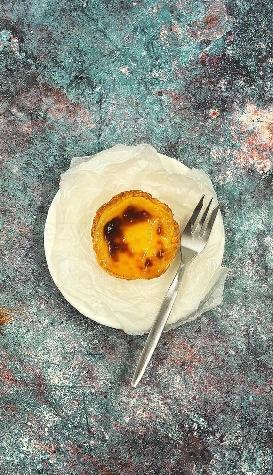 uno pastello de Nata o portoghese uovo crostata su un' bianca piatto. pastello de belm è un' piccolo torta con un' croccante soffio Pasticcino Crosta e un' crema pasticciera crema Riempimento. foto