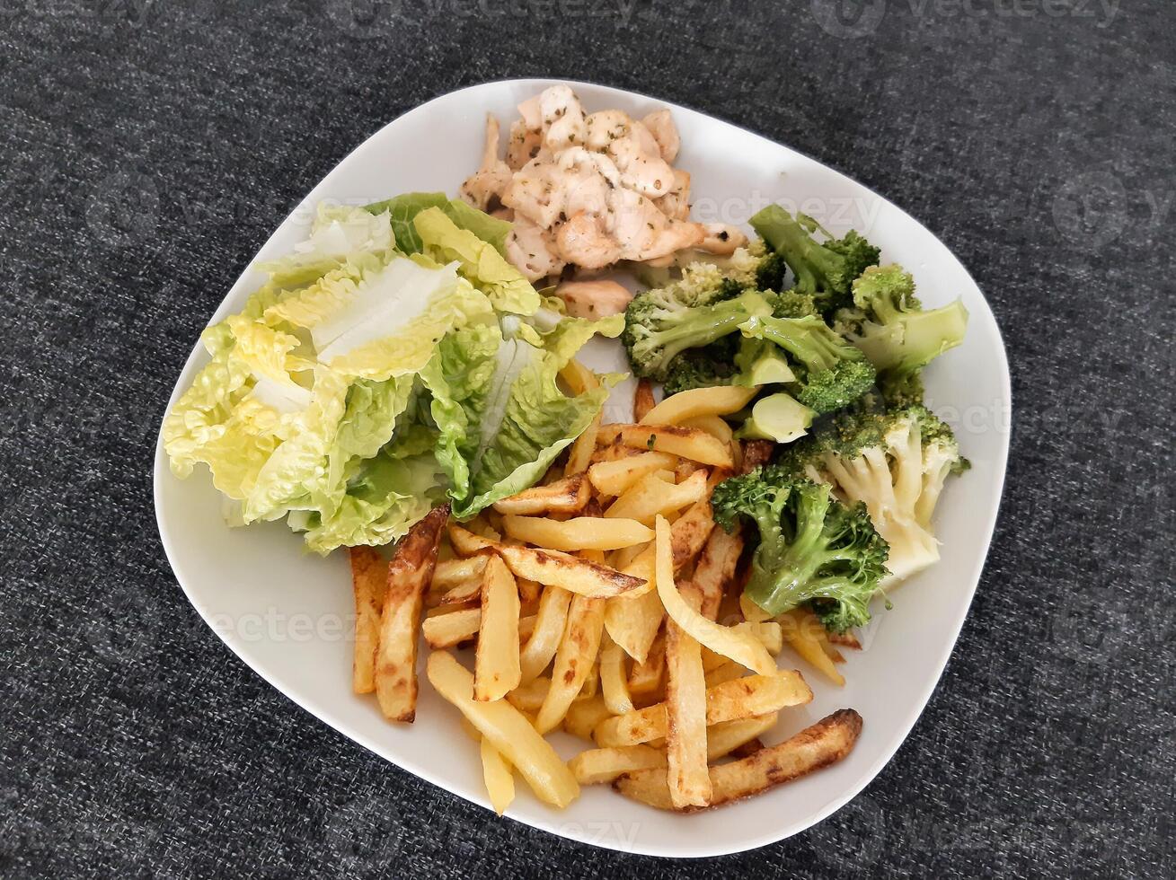 fatti in casa grigliato pollo con francese patatine fritte, broccoli e verde insalata, servito su un' bianca piatto foto