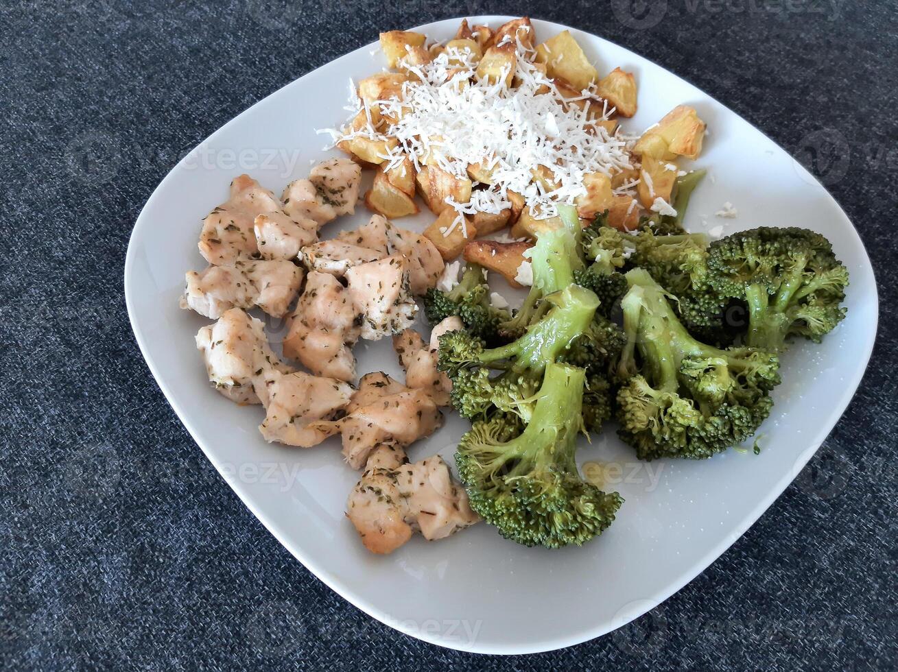 fatti in casa grigliato pollo con francese patatine fritte, formaggio e broccoli, servito su un' bianca piatto foto