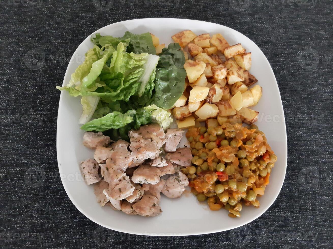 fatti in casa grigliato pollo con francese patatine fritte, verde insalata e pisello stufato servito su un' bianca piatto foto