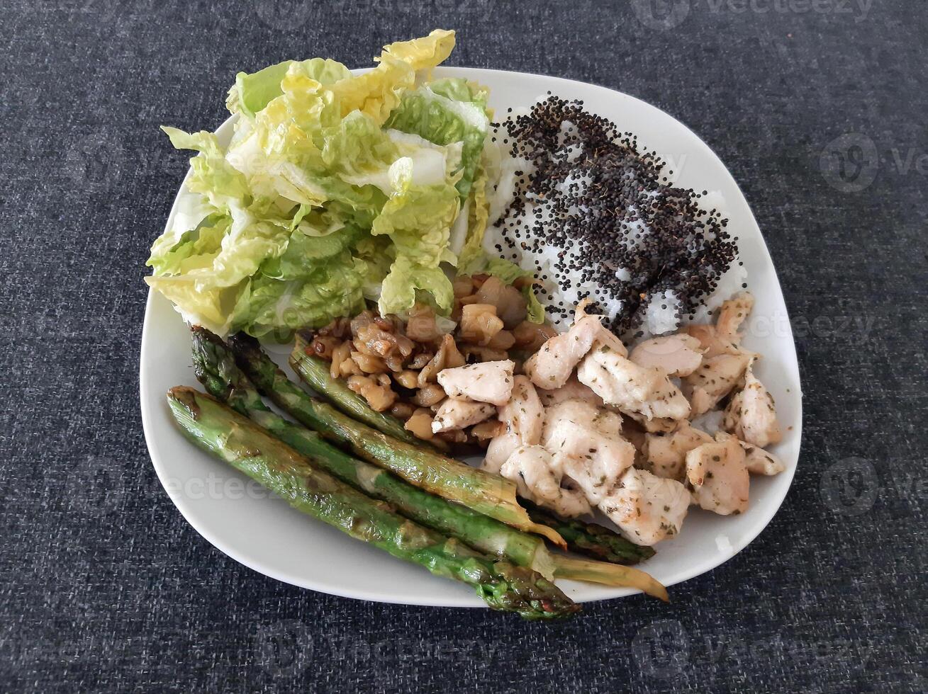 fatti in casa grigliato pollo con Riso, verde insalata e grigliato asparago, servito su un' bianca piatto. brocolli semi su superiore di il riso foto