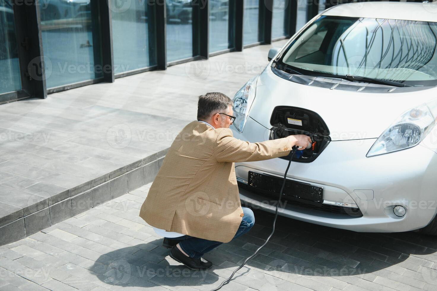 un' uomo d'affari addebiti un elettrico auto foto