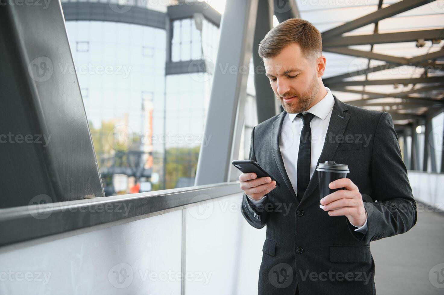 barbuto uomo d'affari nel formale completo da uomo su rompere utilizzando mobile Telefono uso smartphone. attività commerciale uomo in piedi al di fuori su moderno urbano città strada sfondo con caffè tazza nel centro all'aperto. copia spazio foto