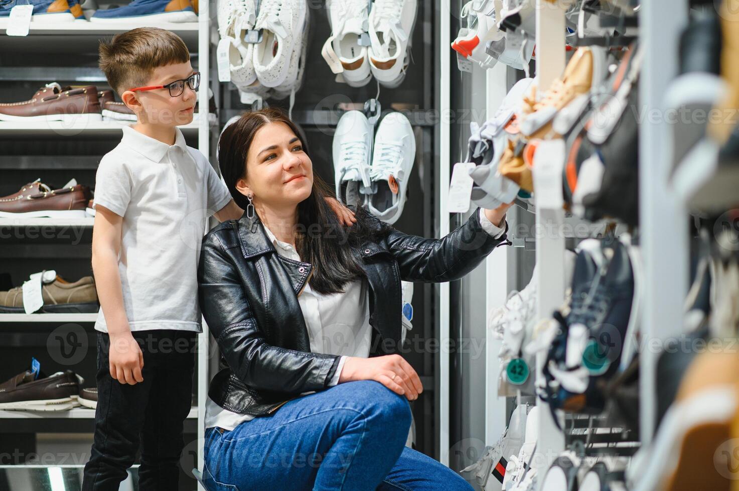 donna con bambino la scelta e provando su nuovo stivali nel shopping centro commerciale foto