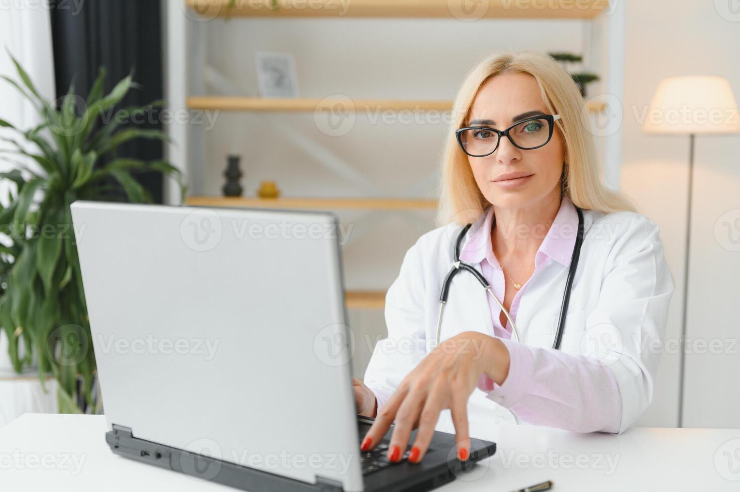ritratto di mezzo età femmina medico è indossare un' bianca medico cappotto con un' stetoscopio in giro sua collo. sorridente medico in piedi a privato clinica foto