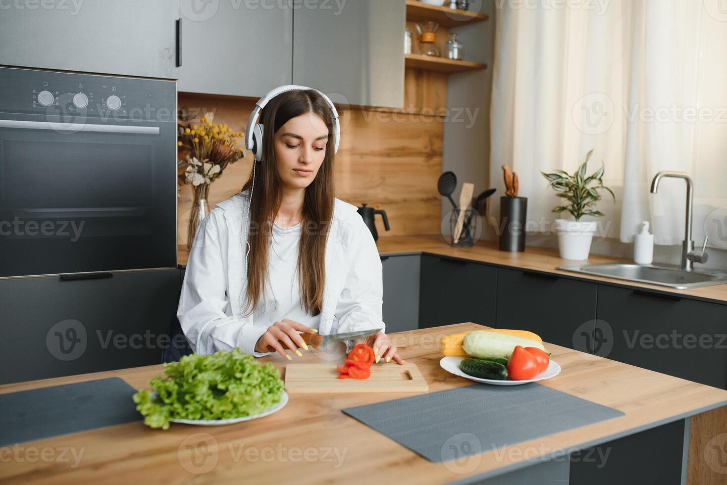 atletico donna blogger dietologo preparare un' insalata con fresco verdure e conduce un' video conferenza su salutare mangiare su il computer portatile nel il cucina foto