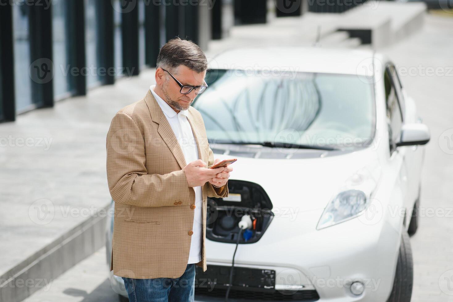 un' uomo d'affari addebiti un elettrico auto foto