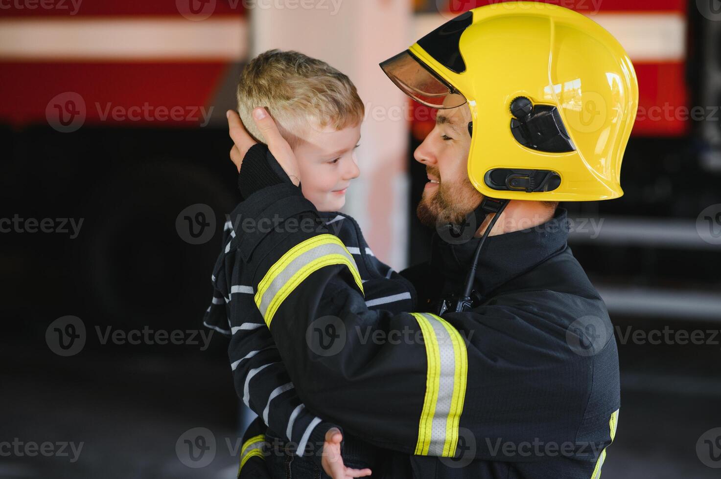 sporco pompiere nel uniforme Tenere poco salvato ragazzo in piedi su nero sfondo. foto