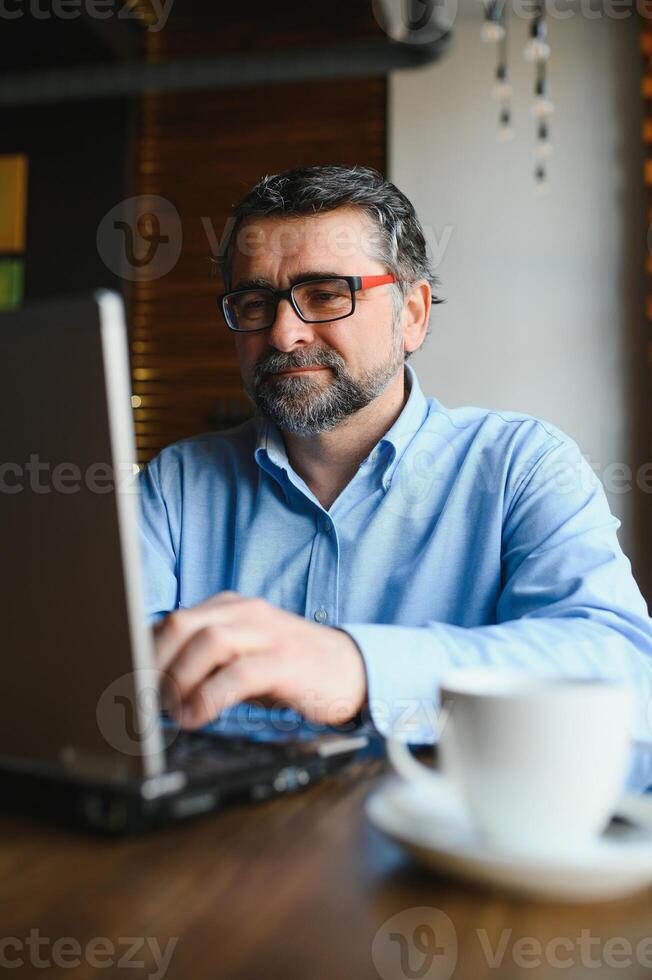 attività commerciale, tecnologia e persone concetto , anziano uomo d'affari con il computer portatile computer potabile caffè a moderno bar. foto