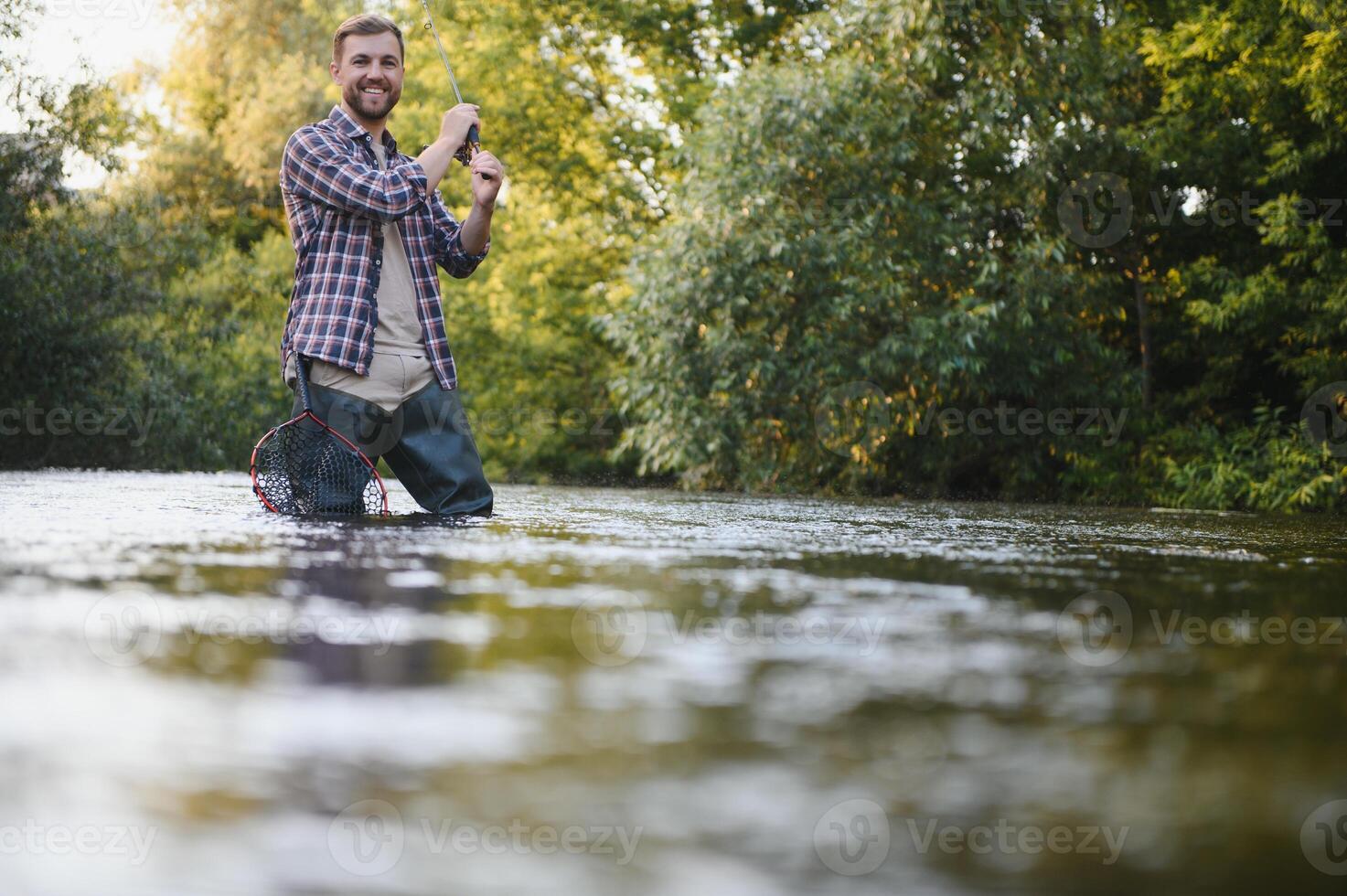 uomo con pesca asta, pescatore uomini nel fiume acqua all'aperto. attraente trota pesce nel rete. estate pesca passatempo foto