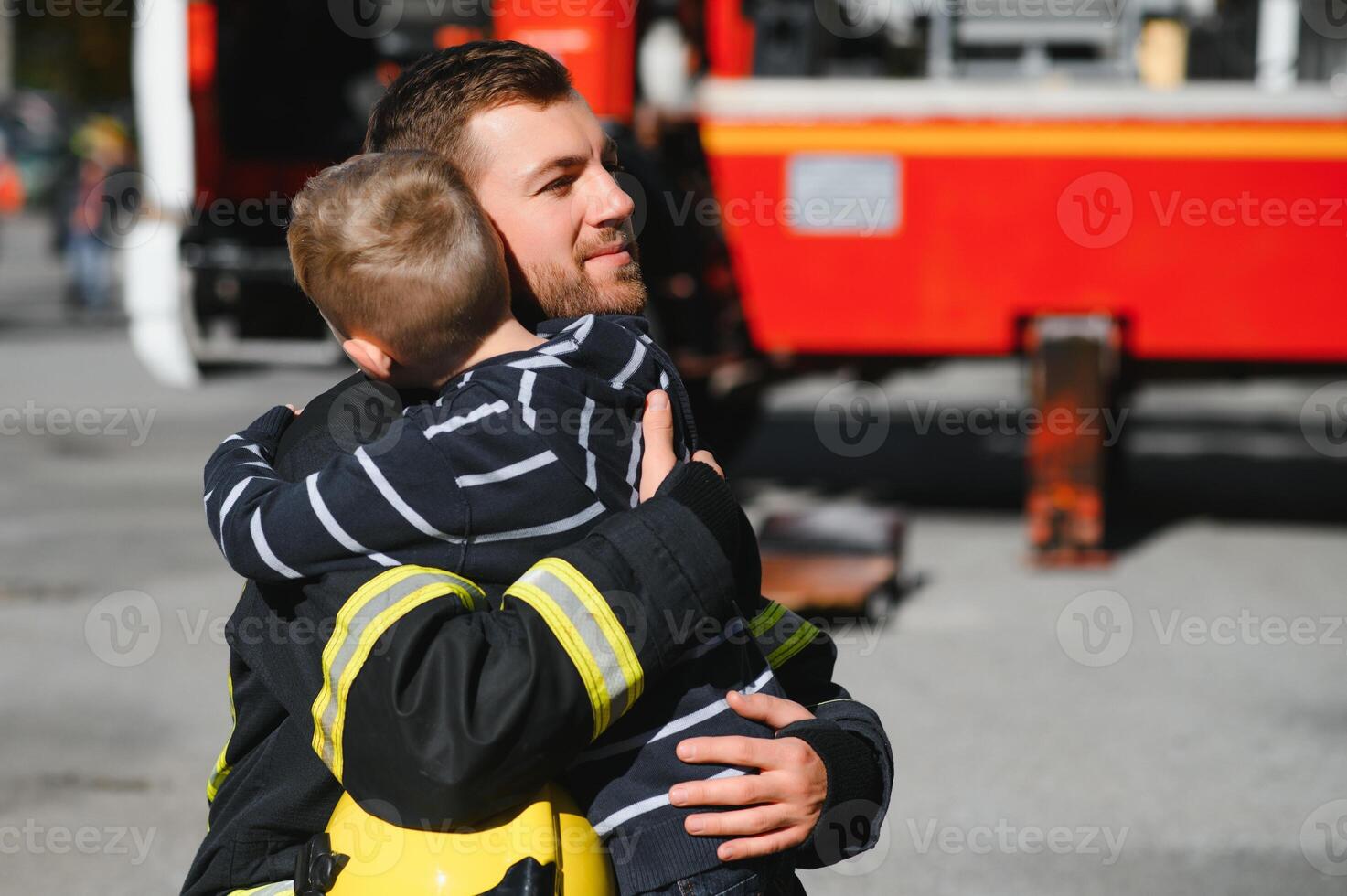 sporco pompiere nel uniforme Tenere poco salvato ragazzo in piedi su nero sfondo. foto