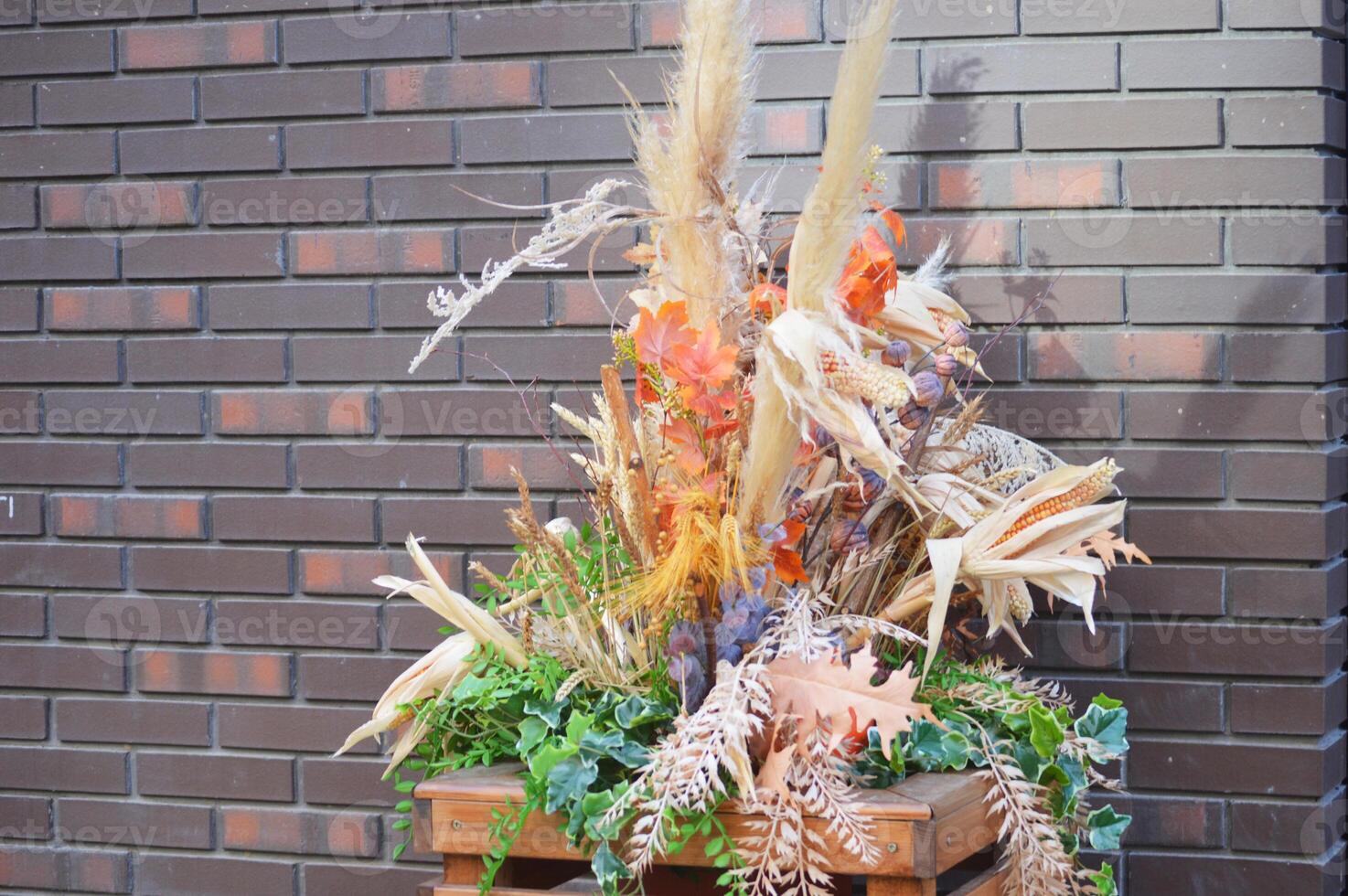 autunno strada arredamento, composizione di secco fiori, le foglie e teste di erba e cereali su il sfondo di un' mattone parete. foto